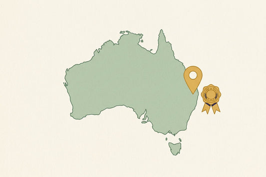 A map of Australia in sage green with a gold location pin on the east coast and a ribbon seal