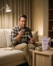 A man on the sofa in the evening with a Restore PM sachet and a spoon of honey, tea on the side table