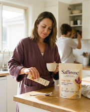 A woman at the kitchen bench in the morning squeezing a Rise AM sachet onto a spoon