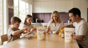 A family of four at the breakfast table, the kids with Bright AM sachets and their mum with a Rise AM sachet, the pouches on the table