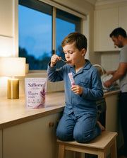 A boy in pyjamas at the kitchen bench in the early evening with a Dream PM sachet and a spoon of honey