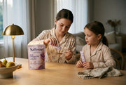 Two sisters in pyjamas at the cleared dinner table, each with a Dream PM sachet