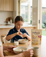 A girl of about eight squeezing a Bright AM sachet onto her porridge at breakfast, the pouch beside her bowl