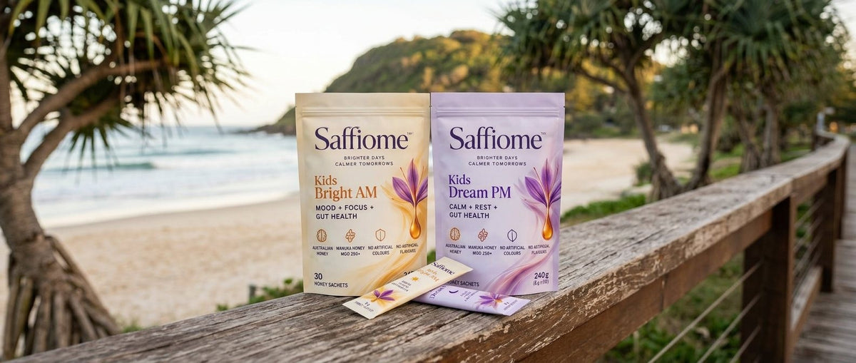 Kids Bright AM and Kids Dream PM pouches on a timber boardwalk rail at Burleigh Heads on the Gold Coast at sunrise, two sachets in front