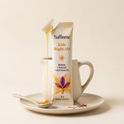 A Kids Bright AM sachet torn open, honey running onto a spoon, saffron threads beside it